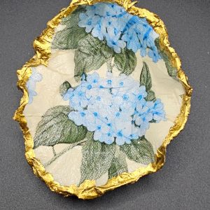 Fragment of decorative napkin featuring blue hydrangea flowers and a gold foil edge.