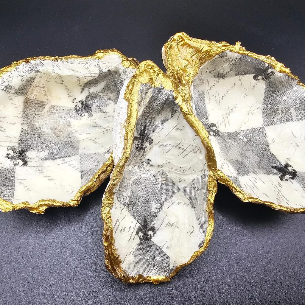 Three white ceramic bowls with jagged gold rims arranged on a dark surface.