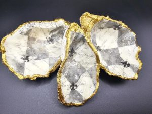 Three white ceramic bowls with jagged gold rims arranged on a dark surface.