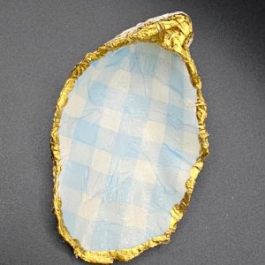 Blue and white checkered oval cutout with crumpled gold foil edge on a dark gray background.